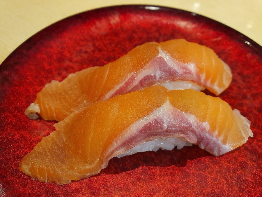 Deux nigiri de saumon posés sur une assiette rouge