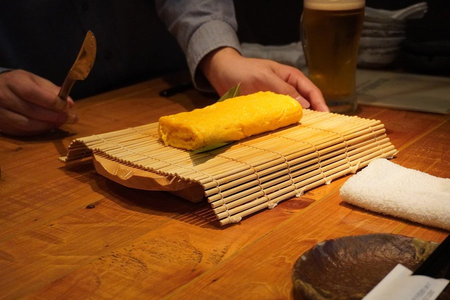 Une omelette roulée posée sur une natte de bambou, sur le comptoir